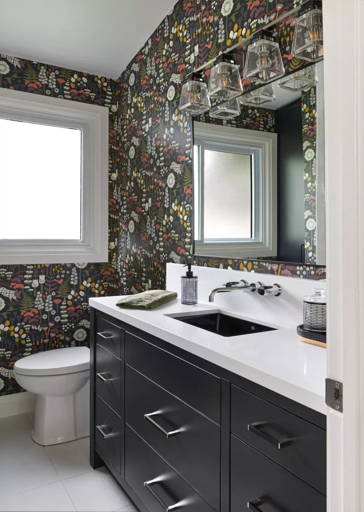 Test out bold design trends in small spaces, like this black bathroom with whimsical woodland wallpaper