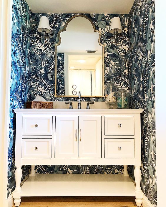 Blue palm print wallpaper in a powder room with white cabinet
