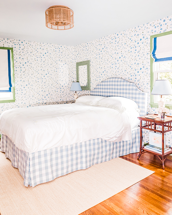 Stunning modern floral farmhouse bedroom featuring green trim, white and blue roman shades, a light blue upholstered bed, and small-scale blue floral vine wallpaper throughout.